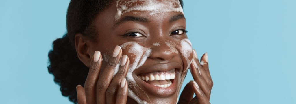 Jovem negra realiza a limpeza facial diária como parte de sua rotina de cuidados com a pele